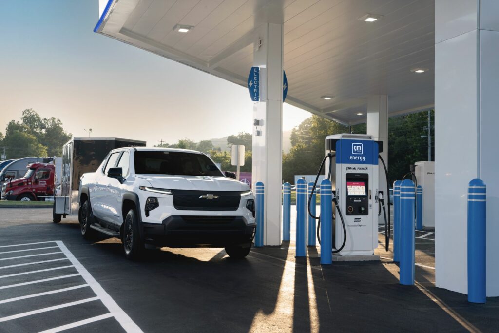 A 2024 Chevrolet Silverado EV WT at a pull-through charging stall located at a flagship Pilot and Flying J travel center, as part of the new coast-to-coast fast charging network.